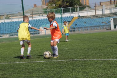 Odessa, Ukrayna - 7 Eylül 2019: Antrenmanda küçük çocuklar futbol oynuyor. Genç çocuklar oyun alanında futbol uyguluyorlar. Çocuklar yeşil futsal sahada futbol oynuyor