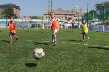 Odessa, Ukrayna - 7 Eylül 2019: Antrenmanda küçük çocuklar futbol oynuyor. Genç çocuklar oyun alanında futbol uyguluyorlar. Çocuklar yeşil futsal sahada futbol oynuyor