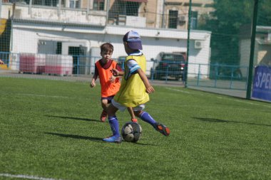 Odessa, Ukrayna - 7 Eylül 2019: Antrenmanda küçük çocuklar futbol oynuyor. Genç çocuklar oyun alanında futbol uyguluyorlar. Çocuklar yeşil futsal sahada futbol oynuyor