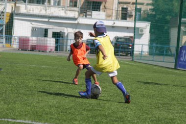 Odessa, Ukrayna - 7 Eylül 2019: Antrenmanda küçük çocuklar futbol oynuyor. Genç çocuklar oyun alanında futbol uyguluyorlar. Çocuklar yeşil futsal sahada futbol oynuyor