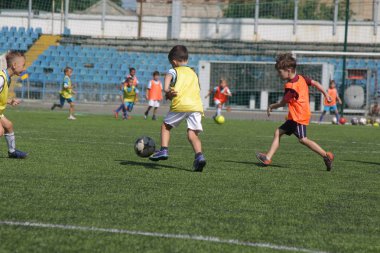 Odessa, Ukrayna - 7 Eylül 2019: Antrenmanda küçük çocuklar futbol oynuyor. Genç çocuklar oyun alanında futbol uyguluyorlar. Çocuklar yeşil futsal sahada futbol oynuyor