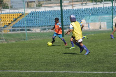 Odessa, Ukrayna - 7 Eylül 2019: Antrenmanda küçük çocuklar futbol oynuyor. Genç çocuklar oyun alanında futbol uyguluyorlar. Çocuklar yeşil futsal sahada futbol oynuyor