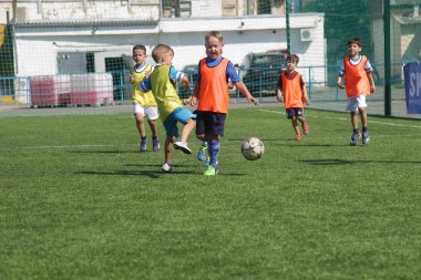 Odessa, Ukrayna - 7 Eylül 2019: Antrenmanda küçük çocuklar futbol oynuyor. Genç çocuklar oyun alanında futbol uyguluyorlar. Çocuklar yeşil futsal sahada futbol oynuyor