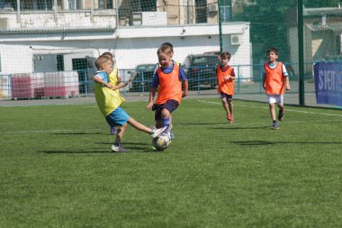 Odessa, Ukrayna - 7 Eylül 2019: Antrenmanda küçük çocuklar futbol oynuyor. Genç çocuklar oyun alanında futbol uyguluyorlar. Çocuklar yeşil futsal sahada futbol oynuyor