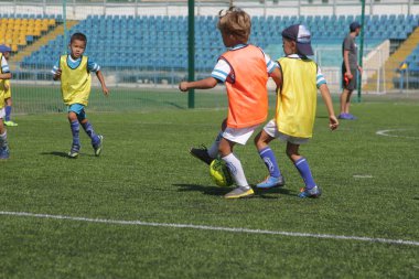 Odessa, Ukrayna - 7 Eylül 2019: Antrenmanda küçük çocuklar futbol oynuyor. Genç çocuklar oyun alanında futbol uyguluyorlar. Çocuklar yeşil futsal sahada futbol oynuyor