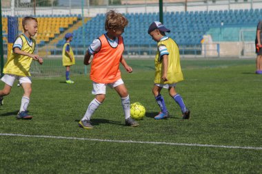 Odessa, Ukrayna - 7 Eylül 2019: Antrenmanda küçük çocuklar futbol oynuyor. Genç çocuklar oyun alanında futbol uyguluyorlar. Çocuklar yeşil futsal sahada futbol oynuyor