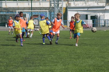 Odessa, Ukrayna - 7 Eylül 2019: Antrenmanda küçük çocuklar futbol oynuyor. Genç çocuklar oyun alanında futbol uyguluyorlar. Çocuklar yeşil futsal sahada futbol oynuyor