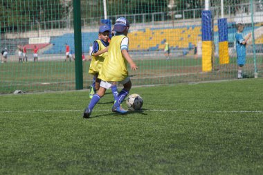 Odessa, Ukrayna - 7 Eylül 2019: Antrenmanda küçük çocuklar futbol oynuyor. Genç çocuklar oyun alanında futbol uyguluyorlar. Çocuklar yeşil futsal sahada futbol oynuyor
