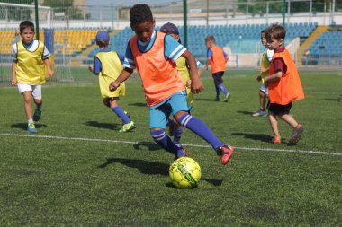 Odessa, Ukrayna - 7 Eylül 2019: Antrenmanda küçük çocuklar futbol oynuyor. Genç çocuklar oyun alanında futbol uyguluyorlar. Çocuklar yeşil futsal sahada futbol oynuyor