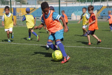 Odessa, Ukrayna - 7 Eylül 2019: Antrenmanda küçük çocuklar futbol oynuyor. Genç çocuklar oyun alanında futbol uyguluyorlar. Çocuklar yeşil futsal sahada futbol oynuyor
