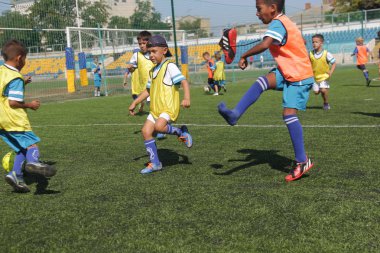 Odessa, Ukrayna - 7 Eylül 2019: Antrenmanda küçük çocuklar futbol oynuyor. Genç çocuklar oyun alanında futbol uyguluyorlar. Çocuklar yeşil futsal sahada futbol oynuyor