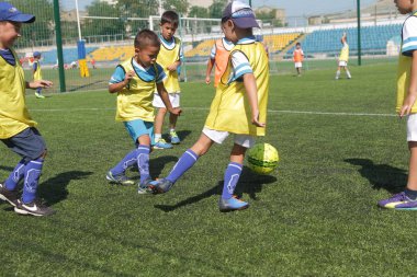 Odessa, Ukrayna - 7 Eylül 2019: Antrenmanda küçük çocuklar futbol oynuyor. Genç çocuklar oyun alanında futbol uyguluyorlar. Çocuklar yeşil futsal sahada futbol oynuyor