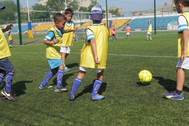 Odessa, Ukrayna - 7 Eylül 2019: Antrenmanda küçük çocuklar futbol oynuyor. Genç çocuklar oyun alanında futbol uyguluyorlar. Çocuklar yeşil futsal sahada futbol oynuyor