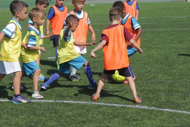 Odessa, Ukrayna - 7 Eylül 2019: Antrenmanda küçük çocuklar futbol oynuyor. Genç çocuklar oyun alanında futbol uyguluyorlar. Çocuklar yeşil futsal sahada futbol oynuyor