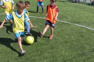 Odessa, Ukrayna - 7 Eylül 2019: Antrenmanda küçük çocuklar futbol oynuyor. Genç çocuklar oyun alanında futbol uyguluyorlar. Çocuklar yeşil futsal sahada futbol oynuyor
