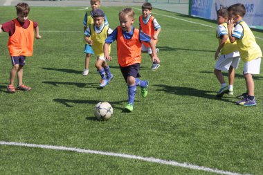 Odessa, Ukrayna - 7 Eylül 2019: Antrenmanda küçük çocuklar futbol oynuyor. Genç çocuklar oyun alanında futbol uyguluyorlar. Çocuklar yeşil futsal sahada futbol oynuyor