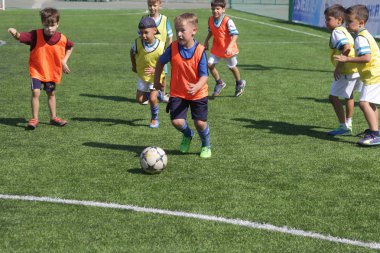 Odessa, Ukrayna - 7 Eylül 2019: Antrenmanda küçük çocuklar futbol oynuyor. Genç çocuklar oyun alanında futbol uyguluyorlar. Çocuklar yeşil futsal sahada futbol oynuyor