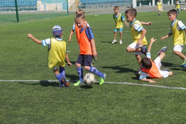 Odessa, Ukrayna - 7 Eylül 2019: Antrenmanda küçük çocuklar futbol oynuyor. Genç çocuklar oyun alanında futbol uyguluyorlar. Çocuklar yeşil futsal sahada futbol oynuyor