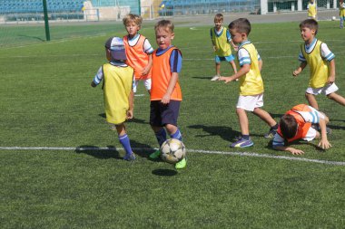 Odessa, Ukrayna - 7 Eylül 2019: Antrenmanda küçük çocuklar futbol oynuyor. Genç çocuklar oyun alanında futbol uyguluyorlar. Çocuklar yeşil futsal sahada futbol oynuyor