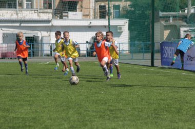 Odessa, Ukrayna - 7 Eylül 2019: Antrenmanda küçük çocuklar futbol oynuyor. Genç çocuklar oyun alanında futbol uyguluyorlar. Çocuklar yeşil futsal sahada futbol oynuyor