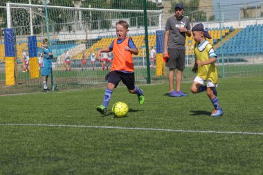 Odessa, Ukrayna - 7 Eylül 2019: Antrenmanda küçük çocuklar futbol oynuyor. Genç çocuklar oyun alanında futbol uyguluyorlar. Çocuklar yeşil futsal sahada futbol oynuyor