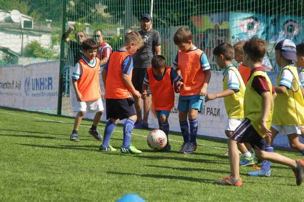 Odessa, Ukrayna - 7 Eylül 2019: Antrenmanda küçük çocuklar futbol oynuyor. Genç çocuklar oyun alanında futbol uyguluyorlar. Çocuklar yeşil futsal sahada futbol oynuyor