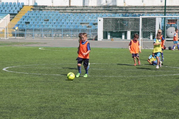 Odessa, Ukrayna - 7 Eylül 2019: Antrenmanda küçük çocuklar futbol oynuyor. Genç çocuklar oyun alanında futbol uyguluyorlar. Çocuklar yeşil futsal sahada futbol oynuyor