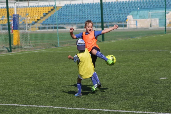 Odessa, Ukrayna - 7 Eylül 2019: Antrenmanda küçük çocuklar futbol oynuyor. Genç çocuklar oyun alanında futbol uyguluyorlar. Çocuklar yeşil futsal sahada futbol oynuyor