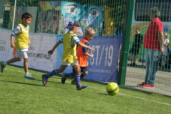 Odessa, Ukrayna - 7 Eylül 2019: Antrenmanda küçük çocuklar futbol oynuyor. Genç çocuklar oyun alanında futbol uyguluyorlar. Çocuklar yeşil futsal sahada futbol oynuyor
