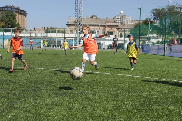 Odessa, Ukrayna - 7 Eylül 2019: Antrenmanda küçük çocuklar futbol oynuyor. Genç çocuklar oyun alanında futbol uyguluyorlar. Çocuklar yeşil futsal sahada futbol oynuyor
