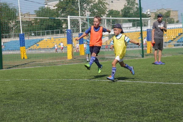 Odessa, Ukrayna - 7 Eylül 2019: Antrenmanda küçük çocuklar futbol oynuyor. Genç çocuklar oyun alanında futbol uyguluyorlar. Çocuklar yeşil futsal sahada futbol oynuyor