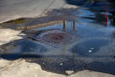 Su temini, kanalizasyon kazası. Karayolu kanalizasyon sisteminin ambarından su akar. Kirli kanalizasyon yol boyunca çeşme aşağı akar. Ambardan su akar. Çeşme kanalizasyondan yola akar