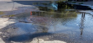 Su temini, kanalizasyon kazası. Karayolu kanalizasyon sisteminin ambarından su akar. Kirli kanalizasyon yol boyunca çeşme aşağı akar. Ambardan su akar. Çeşme kanalizasyondan yola akar