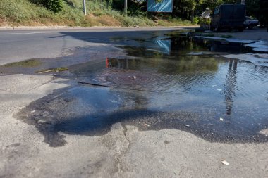 Su temini, kanalizasyon kazası. Karayolu kanalizasyon sisteminin ambarından su akar. Kirli kanalizasyon yol boyunca çeşme aşağı akar. Ambardan su akar. Çeşme kanalizasyondan yola akar