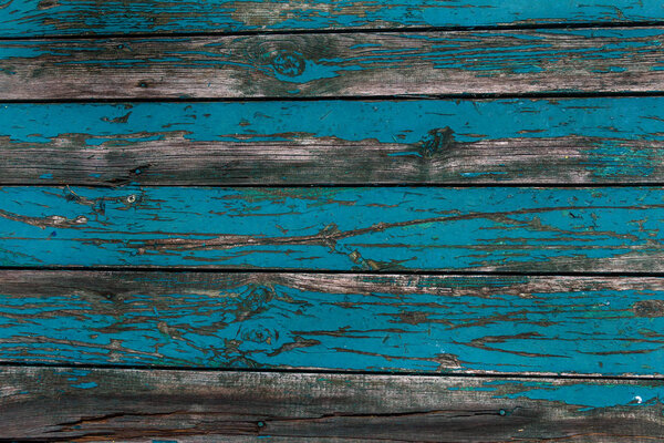 Старые потрепанные деревянные доски с потрескавшейся краской, задний план. Фон старого дерева с большими трещинами и следами старой краски
