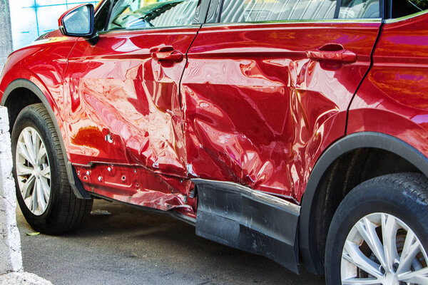 The body of the car is damaged as a result of an accident. High speed head on a car  traffic accident. Dents on the car body after a collision on the highway