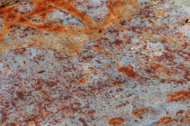 Paslı arka plan. Eski paslı bir metal parçası yolda yatıyor ve eski çatlak asfaltta büyük bir deliği kapatıyor. Kötü asfalt yol