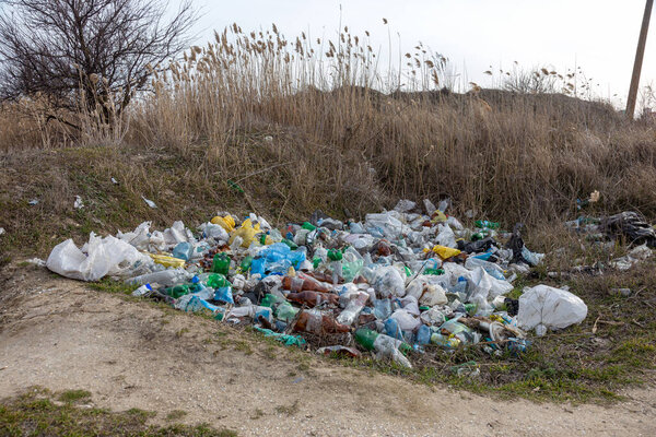 Вылитой мусор на морском побережье оставляют туристы и отдыхающие. Грязный морской песчаный берег моря. Загрязнение окружающей среды Экологическая проблема имеет негативное влияние. Пустые использованные пластиковые бутылки
