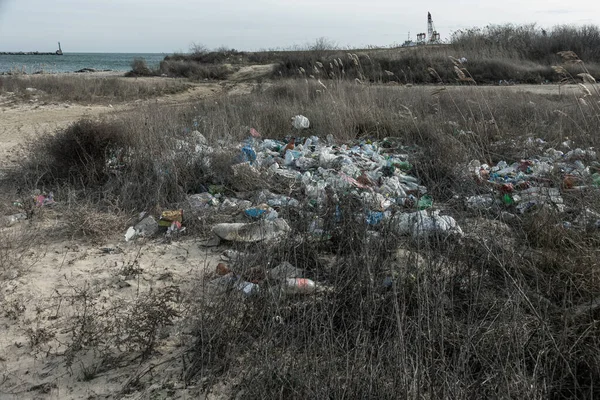 Poured garbage on Sea coast is left by tourists and vacationers. Dirty sea sandy shore of  Sea. Environmental pollution. Environmental problem has negative impact. Empty used dirty plastic bottles