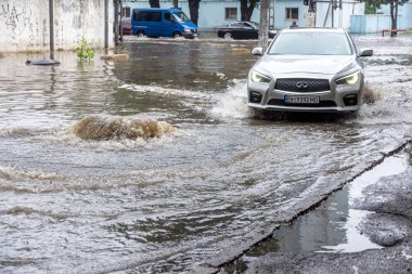 Odessa, Ukrayna - 28 Mayıs 2020: sel baskınları sırasında sel basmış yolda araba kullanmak. Arabalar suda yüzer, sokakları su basar. Arabanın üzerine su sıçradı. Büyük su birikintileriyle dolu şehir yolu.