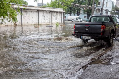 Odessa, Ukrayna - 28 Mayıs 2020: sel baskınları sırasında sel basmış yolda araba kullanmak. Arabalar suda yüzer, sokakları su basar. Arabanın üzerine su sıçradı. Büyük su birikintileriyle dolu şehir yolu.