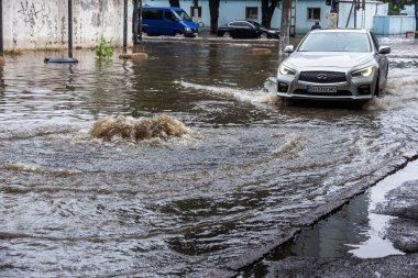 Odessa, Ukrayna - 28 Mayıs 2020: sel baskınları sırasında sel basmış yolda araba kullanmak. Arabalar suda yüzer, sokakları su basar. Arabanın üzerine su sıçradı. Büyük su birikintileriyle dolu şehir yolu.
