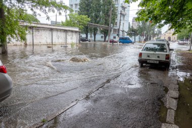 Odessa, Ukrayna - 28 Mayıs 2020: sel baskınları sırasında sel basmış yolda araba kullanmak. Arabalar suda yüzer, sokakları su basar. Arabanın üzerine su sıçradı. Büyük su birikintileriyle dolu şehir yolu.