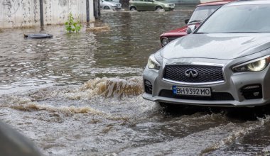 Odessa, Ukrayna - 28 Mayıs 2020: sel baskınları sırasında sel basmış yolda araba kullanmak. Arabalar suda yüzer, sokakları su basar. Arabanın üzerine su sıçradı. Büyük su birikintileriyle dolu şehir yolu.