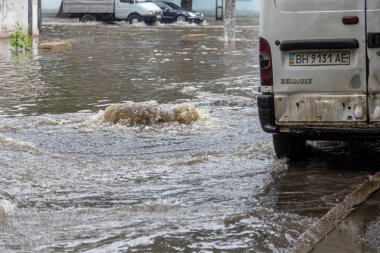 Odessa, Ukrayna - 28 Mayıs 2020: sel baskınları sırasında sel basmış yolda araba kullanmak. Arabalar suda yüzer, sokakları su basar. Arabanın üzerine su sıçradı. Büyük su birikintileriyle dolu şehir yolu.