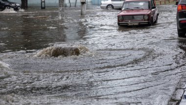 Odessa, Ukrayna - 28 Mayıs 2020: sel baskınları sırasında sel basmış yolda araba kullanmak. Arabalar suda yüzer, sokakları su basar. Arabanın üzerine su sıçradı. Büyük su birikintileriyle dolu şehir yolu.