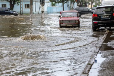 Odessa, Ukrayna - 28 Mayıs 2020: sel baskınları sırasında sel basmış yolda araba kullanmak. Arabalar suda yüzer, sokakları su basar. Arabanın üzerine su sıçradı. Büyük su birikintileriyle dolu şehir yolu.