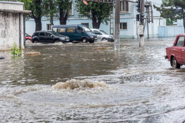 Odessa, Ukrayna - 28 Mayıs 2020: sel baskınları sırasında sel basmış yolda araba kullanmak. Arabalar suda yüzer, sokakları su basar. Arabanın üzerine su sıçradı. Büyük su birikintileriyle dolu şehir yolu.