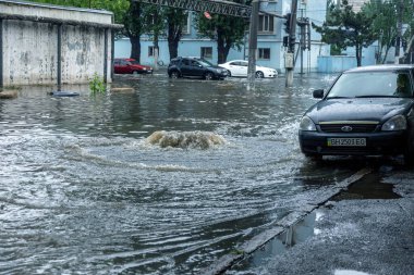 Odessa, Ukrayna - 28 Mayıs 2020: sel baskınları sırasında sel basmış yolda araba kullanmak. Arabalar suda yüzer, sokakları su basar. Arabanın üzerine su sıçradı. Büyük su birikintileriyle dolu şehir yolu.