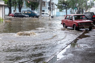 Odessa, Ukrayna - 28 Mayıs 2020: sel baskınları sırasında sel basmış yolda araba kullanmak. Arabalar suda yüzer, sokakları su basar. Arabanın üzerine su sıçradı. Büyük su birikintileriyle dolu şehir yolu.
